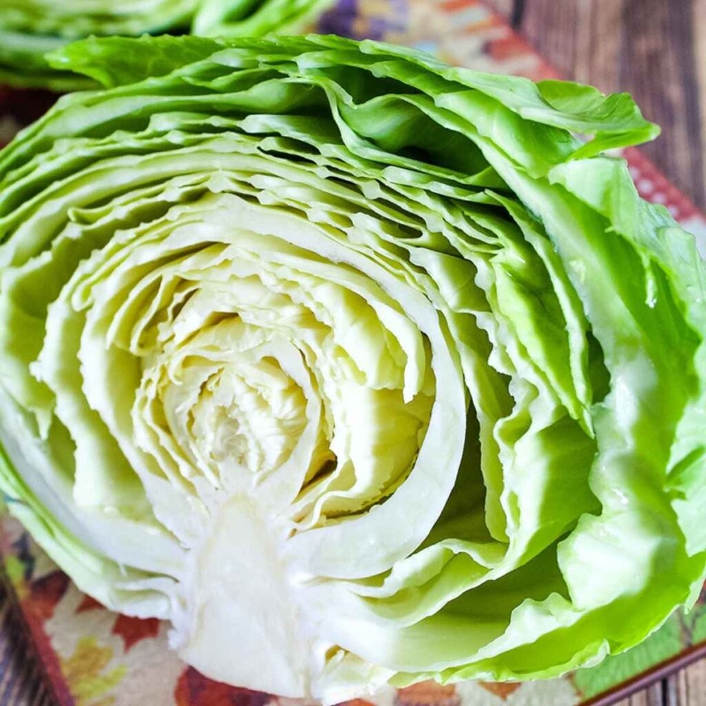 One half of a head of cabbage showing the inside of the vegetable with outer green leaves and yellow tinted leaves in the center.