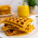 A stack of vegan pumpkin waffles on a white plate.